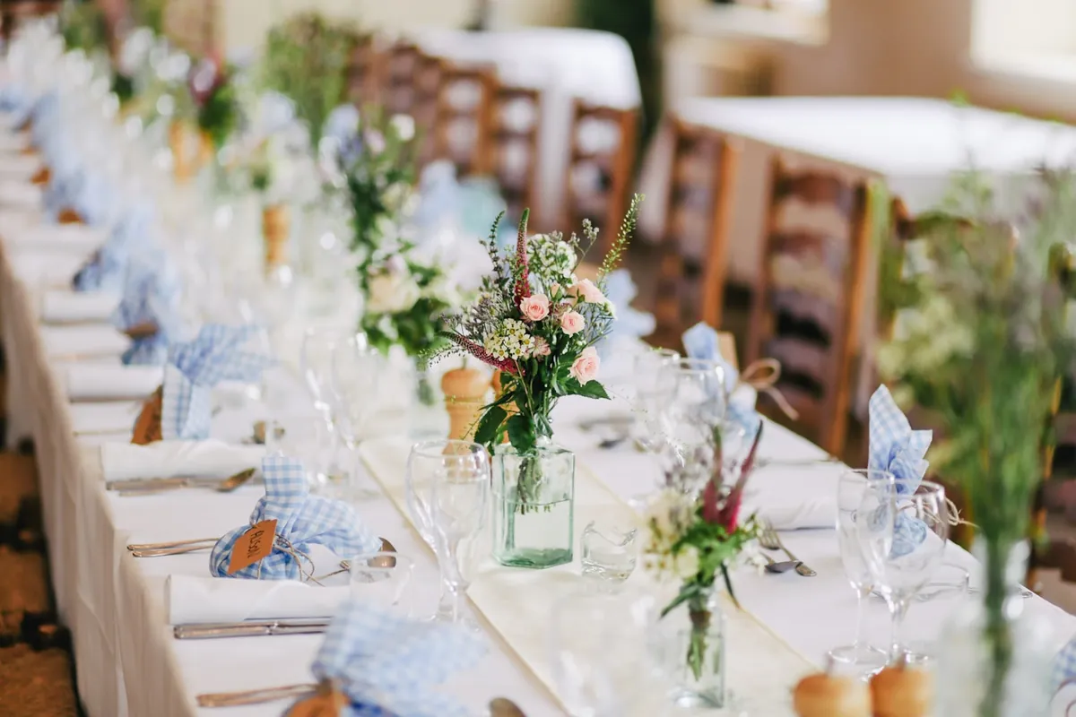 Elegant wedding reception tablescape with tall floral centerpiece and candlelight